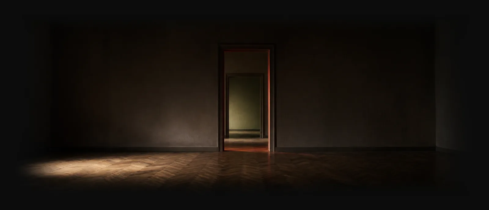 Une pièce entièrement vide au parquet ancien ; au fond, une porte ouverte laisse tomber une lumière chaude sur le sol.
